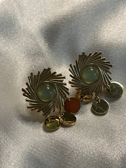 Boucles d'oreilles dorées soleil avec pierre verte et pendentifs ronds.