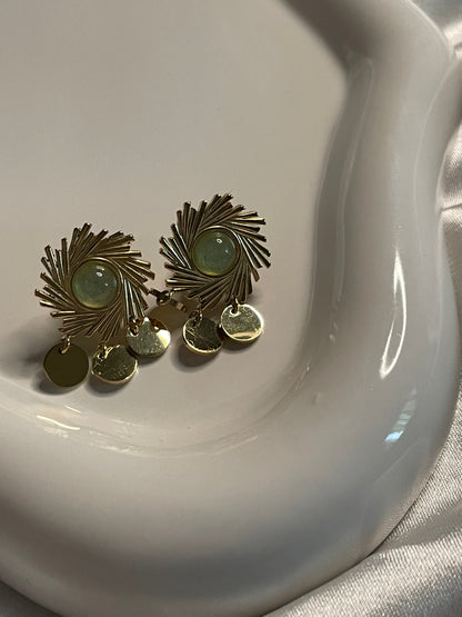 Boucles d'oreilles dorées soleil avec pierre verte et pendentifs ronds.