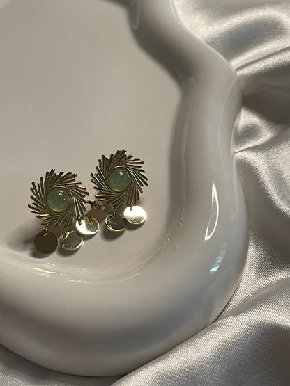 Boucles d'oreilles dorées soleil avec pierre verte et pendentifs ronds.