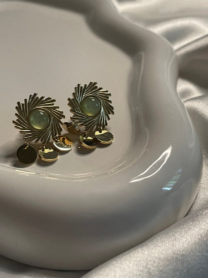 Boucles d'oreilles dorées soleil avec pierre verte et pendentifs ronds.